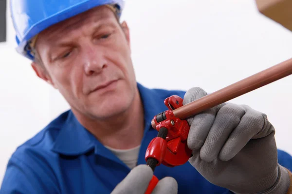 Plumber cutting a copper pipe with a pipe cutter — Stock Photo #8106878