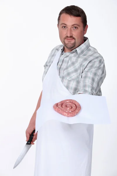 A butcher displaying a coil of sausage