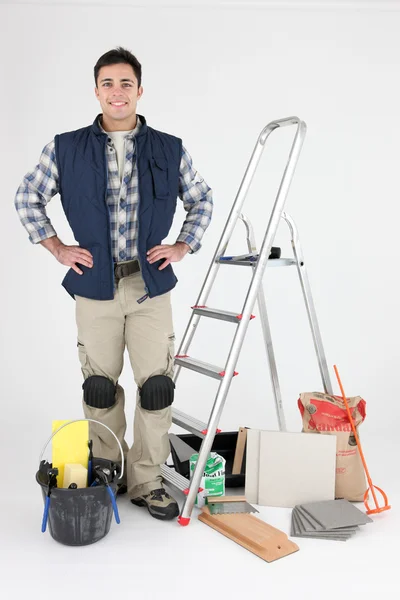 Proud tiler posing near ladder and tools