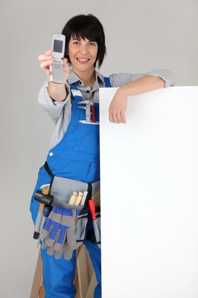 Female manual worker displaying mobile telephone
