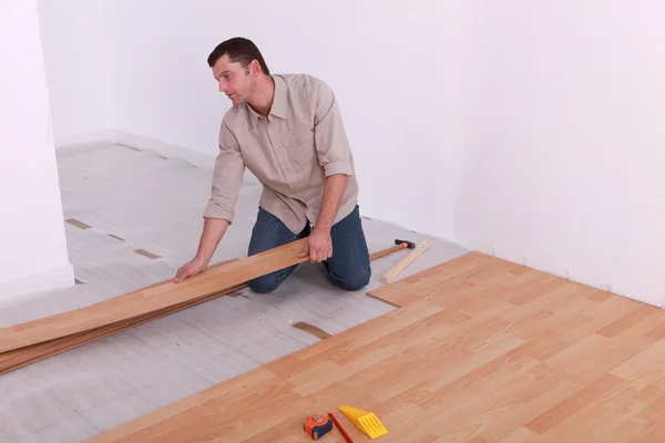 Man renovating the floor with wood panels