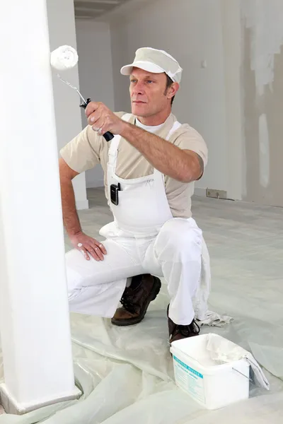 Decorator using roller to paint wall