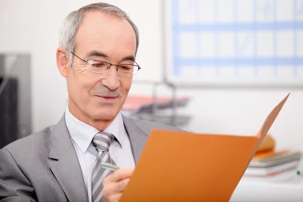 Older businessman writing in a file — Stock Photo #8320691