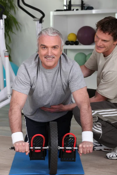 Grey haired man with personal trainer