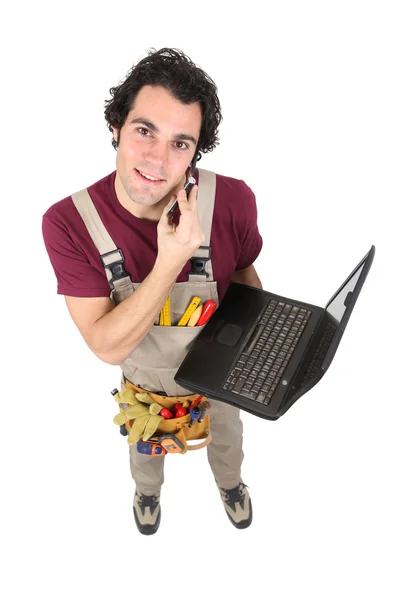 Laborer in dungarees with mobile phone and computer