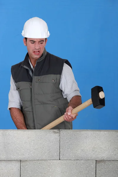 Picture of bricklayer destroying wall with hammer
