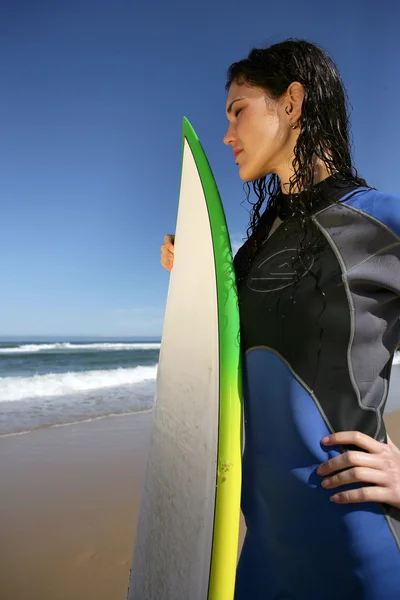 Brunette in wet-suit stood with surfboard