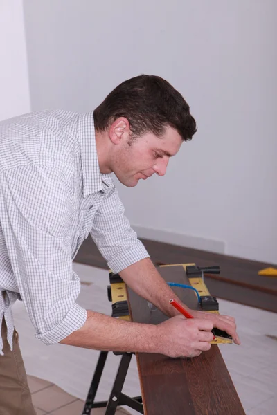 Man marking wooden floor before cutting it