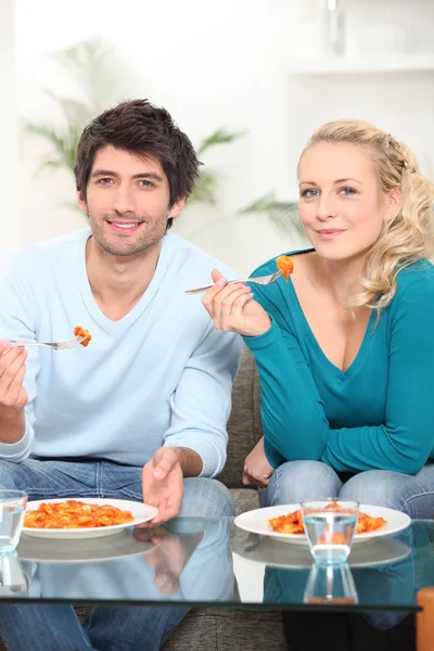 Young couple dining in front of TV