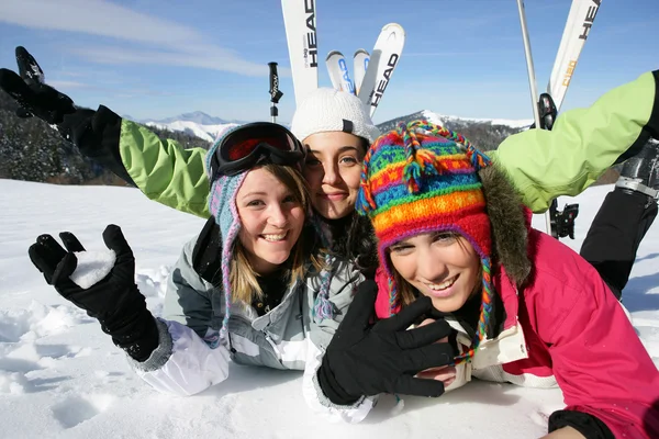 Three female friends laying in the snow