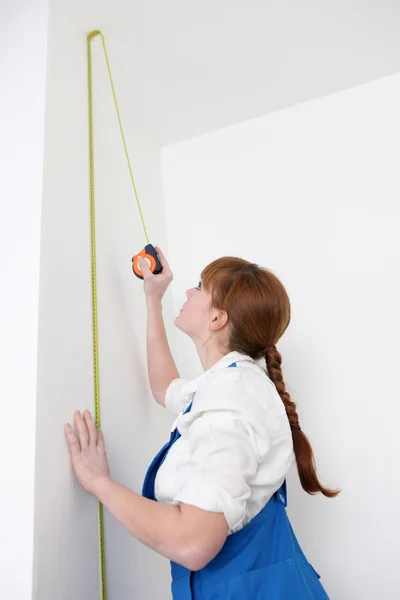 Woman measuring wall