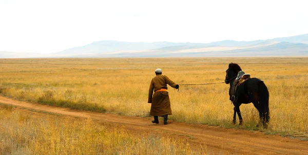 Mongolian man leading a horse