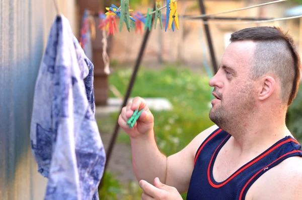 Down syndrome man hanging clothes