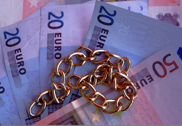 Gold necklace with money in euros in the background