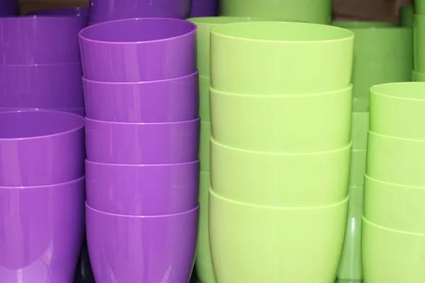 Violets and green plastic pots stacked on sale