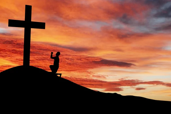 Silhouette of a man praying under the cross