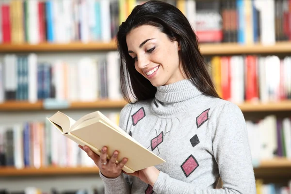 Smiling female student with book in hands in a bookstore