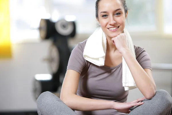Young woman sitting on the gym's floor after workout