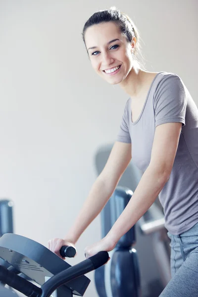 Portrait of young woman riding an exercise bike