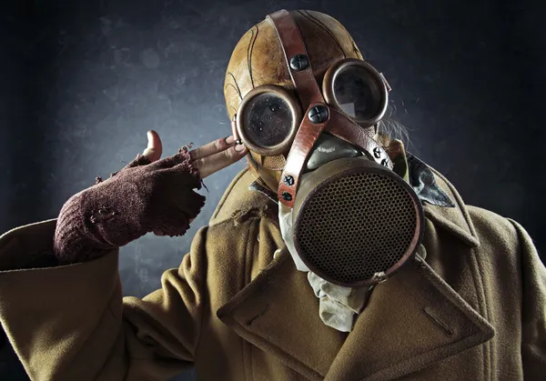 Grunge portrait man in gas mask pointing hand gun at his own hea