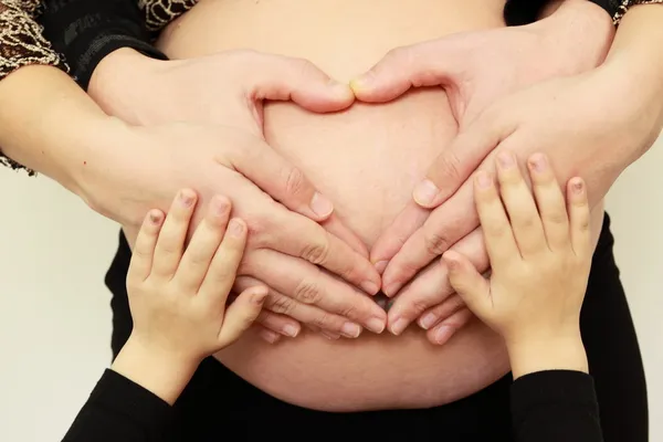 Heart from the hands on a pregnant belly