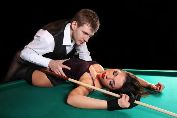 Girl lying on the table for a game of pool and a man hugging her