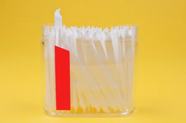 Toothpicks in clear plastic container on yellow