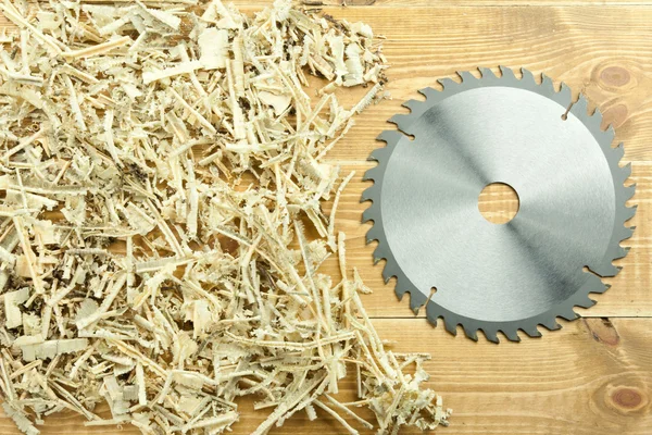 Circular saw blade on a wooden and sawdust background