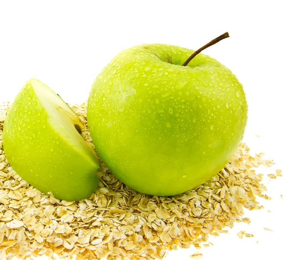 Fresh green apple with a segment on oat flakes.