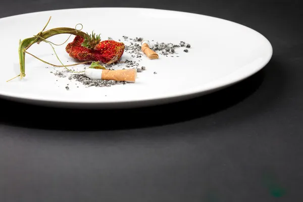 A plate with cigarette and strawberry