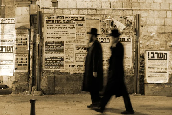 Hasidic jews walking in front of propaganda panels, jerusalem, israel