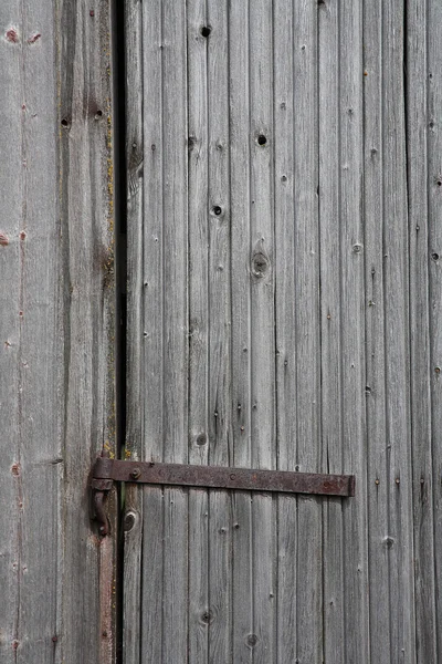 Aged weathered gray old vintage wood door with a rusty hinge