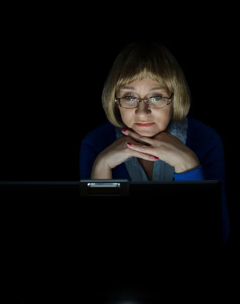 Mature woman working on laptop computer in night