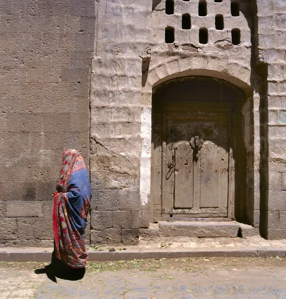 A veiled Muslim woman walks on a Sana’a street, Yemen