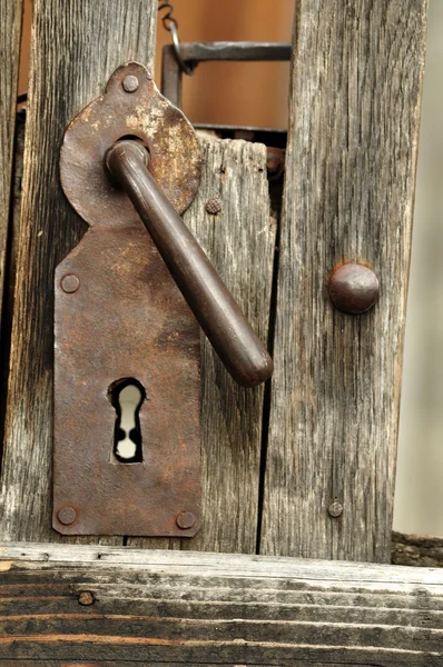A very old door handle on a wooden door
