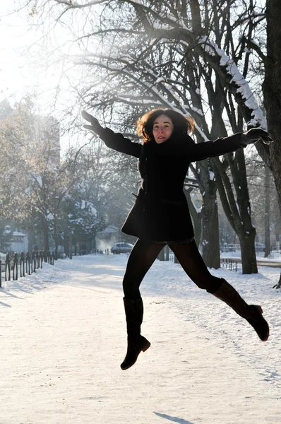 Young woman enjoying winter and jumping in the park