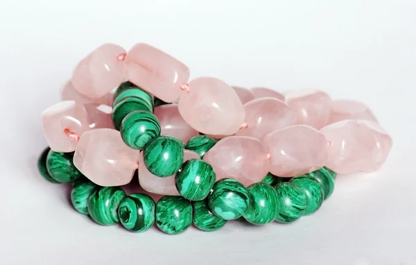 Green malachite and pink quartz necklaces on white background