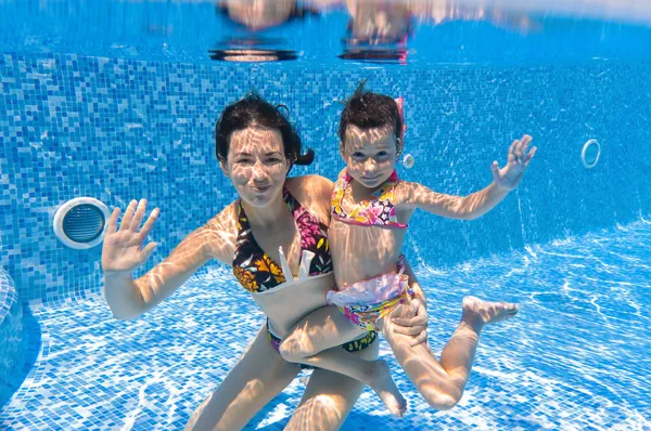 Active underwater smiling family in swimming pool