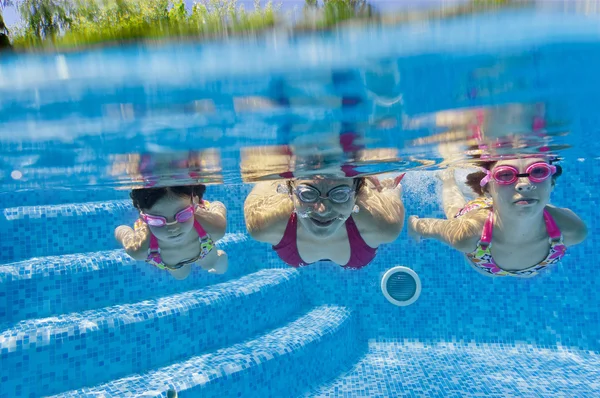 Underwater smiling family having fun and playing in swimming pool