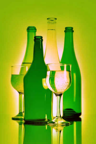 Bottle and wineglass with beverage. Green still-life