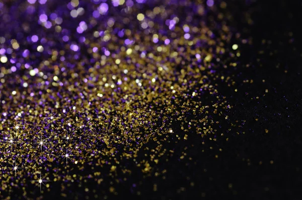 Gold and purple glitter on black background