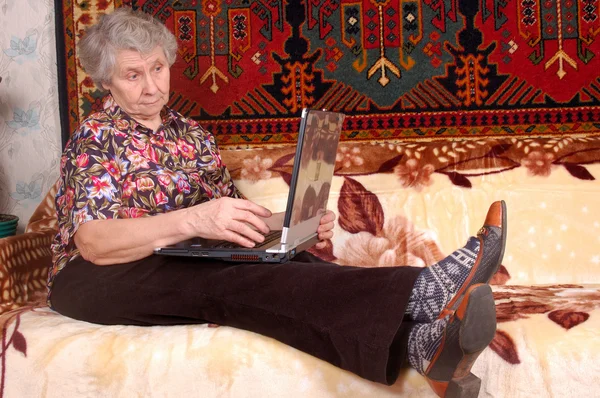 Seventy year old women with laptop on sofa