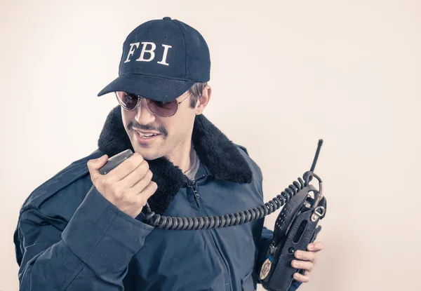 Investigative cocky FBI agent wearing blue jacket, sunglasses, and mustache