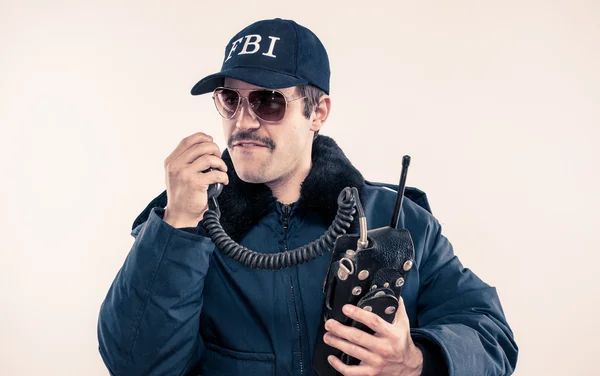 Angry FBI agent in riot jacket about to swear over vintage radio