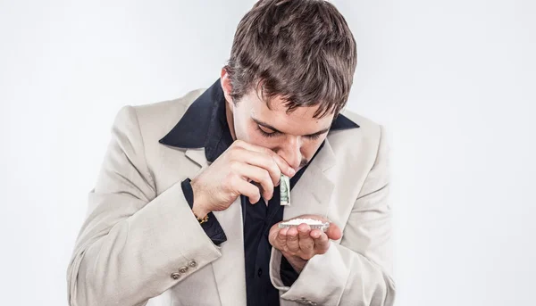 Drug addicted young man doing coke with rolled up dollar in retro suit