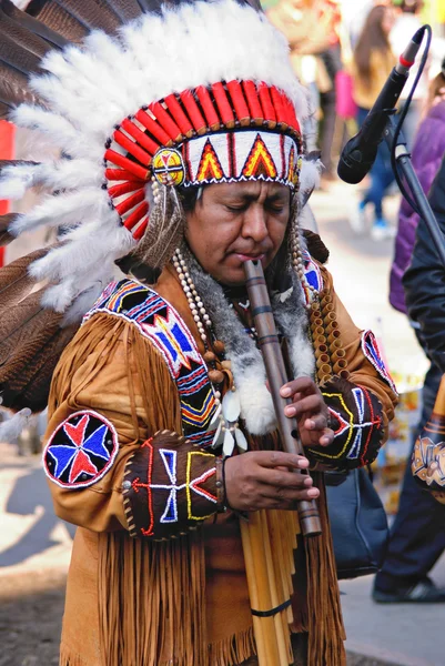 Portrait of a native american playing at a flute