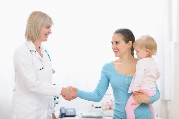 Grateful mom shaking hand to middle age pediatric doctor