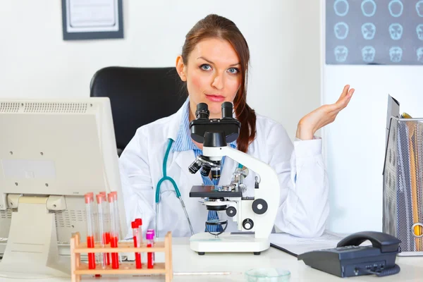 Confused doctor woman working with microscope in laboratory