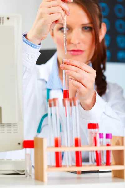Female medical doctor working with test tube at cabinet