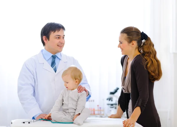 Pediatric doctor talking with mother while baby playing with ste